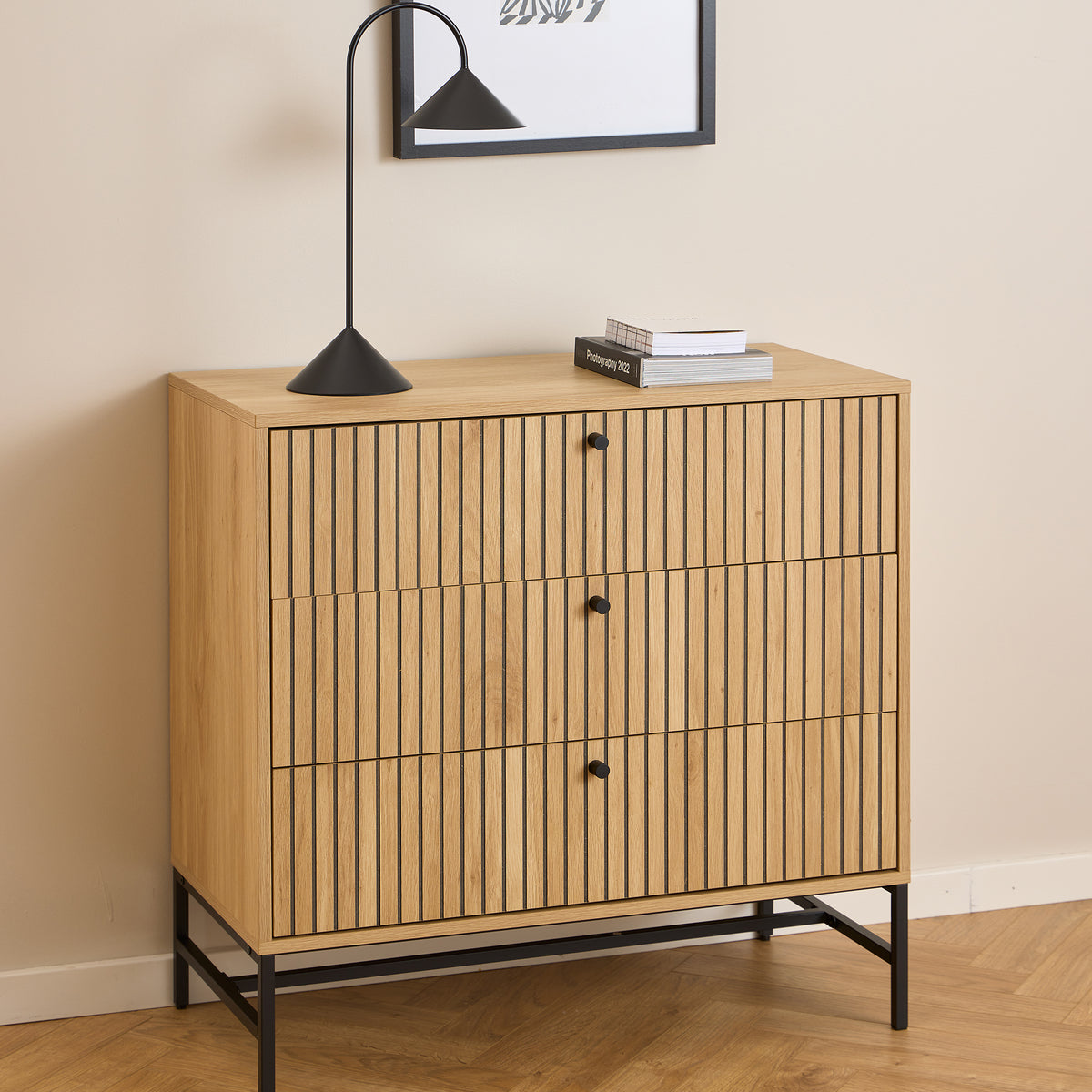 Bambouz chest of drawers (81x81) beneath a wall hanging, with a black lamp and books – a slatted chest of drawers for the living room