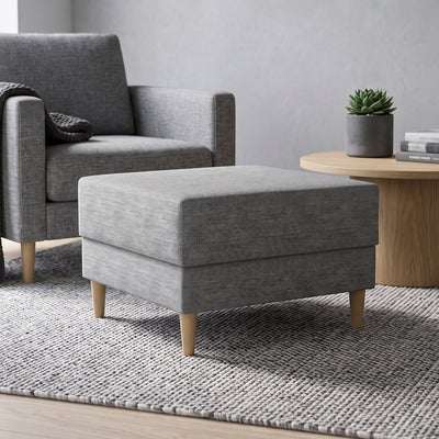 Harmi 66x66 pouffe in the living room in front of a grey armchair, next to a round table with a succulent – pouffe for the living room